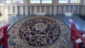 A room with a large rug, wooden beams, and large windows overlooking a body of water. - Lake George Crawford House (Lake George)