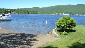 A lake with a boat docked on the left, surrounded by greenery and hills in the background. - Lake George Crawford House (Lake George)