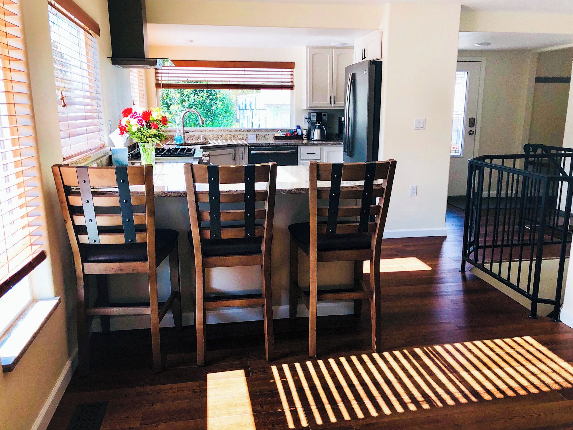 A modern kitchen with wooden chairs, a refrigerator, and a dining island.