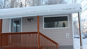 A single-story mobile home with a wooden deck and a covered porch.