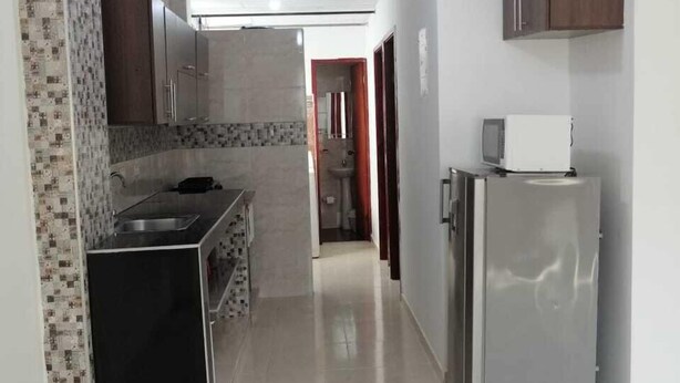 A kitchen with a refrigerator, microwave, and a sink. - Apartamentos Nayibe (Cartagena)