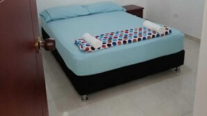 A bedroom with a bed, a nightstand, an air conditioner, and a window with curtains. - Apartamentos Nayibe (Cartagena)