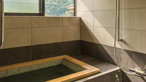 Un baño moderno con una bañera grande, ducha y ventana con vistas a una zona boscosa.