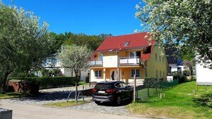 A two-story house with a red-tiled roof, a balcony, and a parked car in the driveway. - Apartment 12 - apartment / apartment in Binz (Binz)