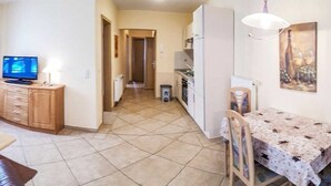 A living room with a leather sofa, a TV, a wooden cabinet, and a dining area with a table and chairs. - Apartment 12 - apartment / apartment in Binz (Binz)