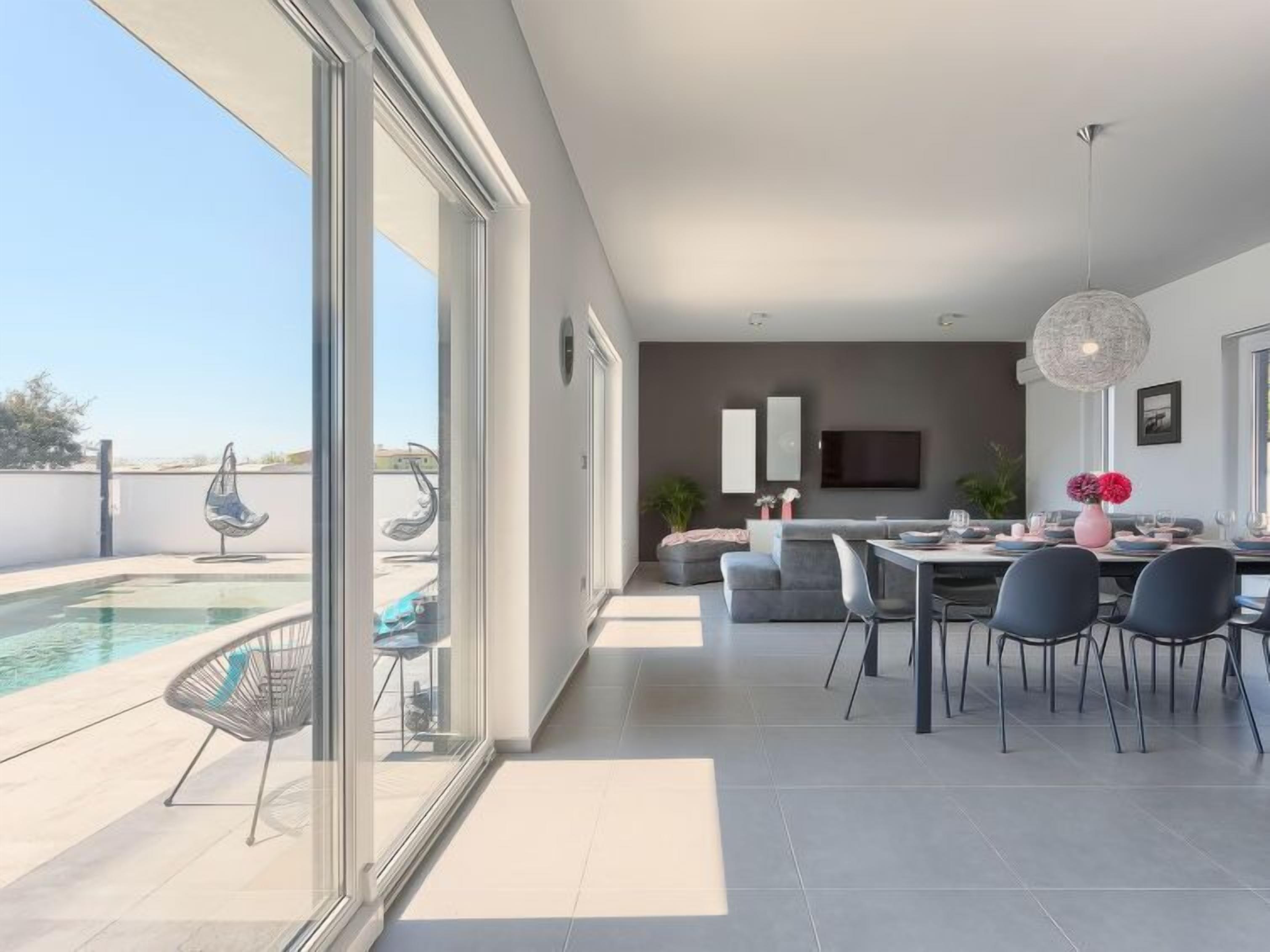 A modern living room with a pool, dining area, and a TV mounted on the wall.