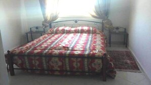 Une chambre à coucher avec un lit, une table de chevet et une fenêtre avec des rideaux.