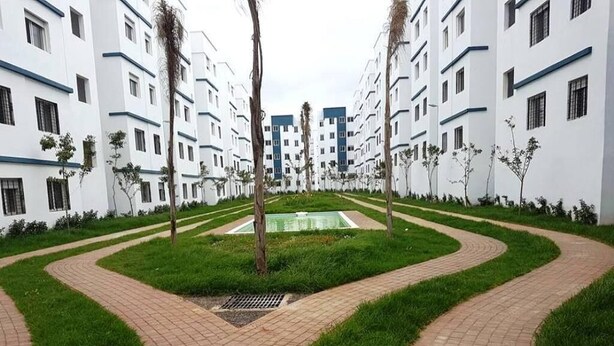 Un ensemble de bâtiments résidentiels comprenant une cour intérieure, des allées pavées et de petits arbres.