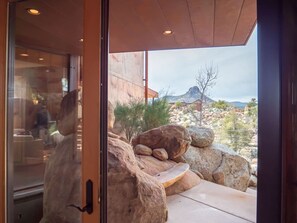 Un edificio moderno con entrada de vidrio, grandes rocas y vistas a un paisaje montañoso.