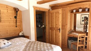 A bedroom with a bed, a wooden desk, and a mirror.
