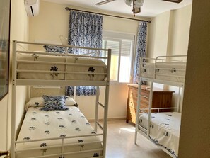 Ein Zimmer mit Etagenbetten, einem Vorhangfenster, einem Deckenventilator und einer Holzkammer.