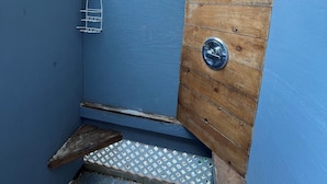 Ett utomhusområde som är målat i blått, med en trädörr, en grind av metall och ett litet trappsteg som leder upp till en terrass.