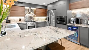 A modern kitchen with a marble countertop, stainless steel appliances, and wooden cabinetry. - Luxury Mountainside Retreat at Silver Star — 3 King En-Suites (Park City)