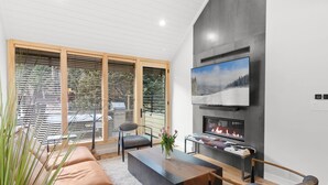 A modern living room with a fireplace, a large TV, and comfortable seating. - Luxury Mountainside Retreat at Silver Star — 3 King En-Suites (Park City)