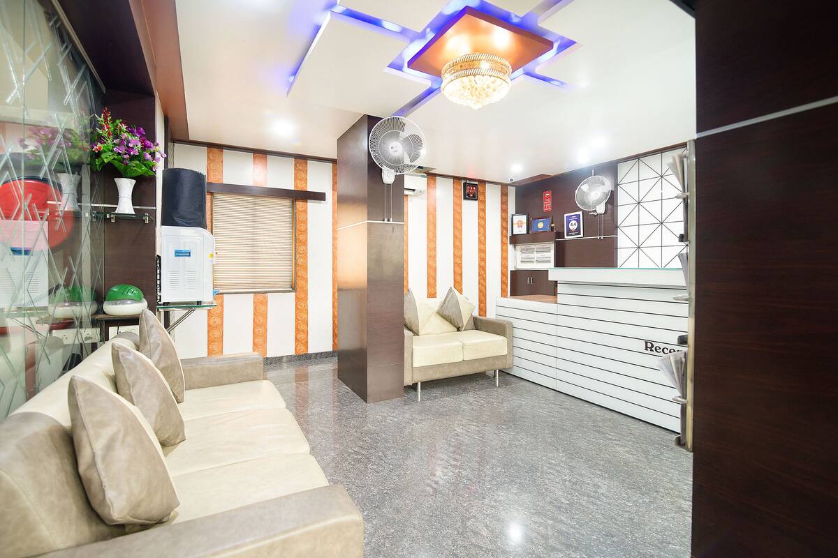 A reception area with a sofa, a fan, a chandelier, and a reception desk.