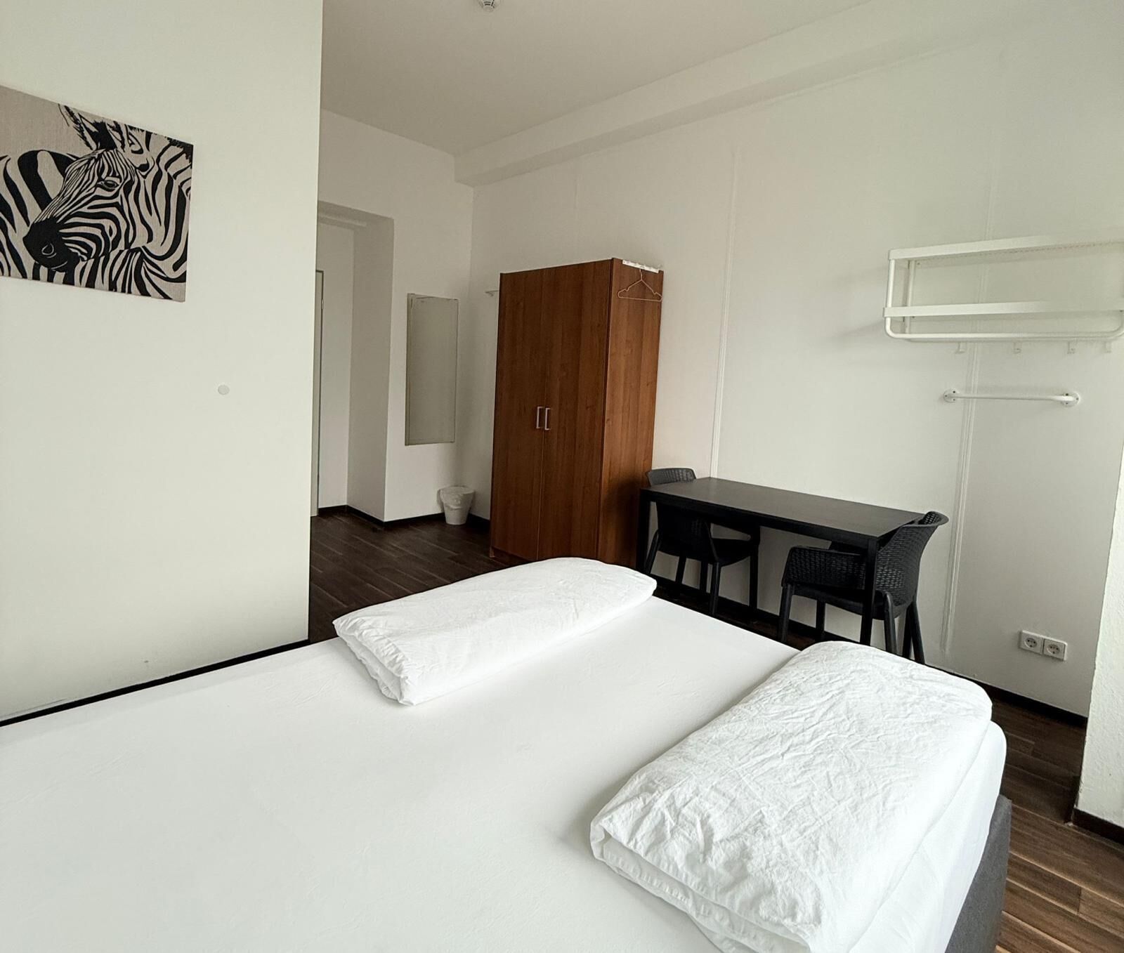 A hotel room with a bed, a desk, and a wardrobe.