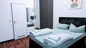 A modern bedroom with a large bed, a wardrobe, a mirror, and a patterned wall.