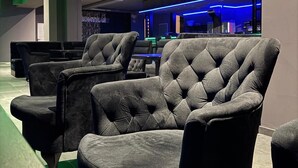 Un área de descanso moderna con sillones capitonados y una zona de bar con iluminación de neón.