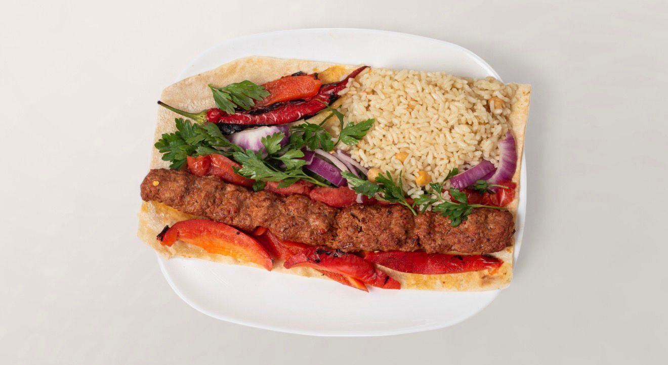 Une assiette composée de kebab, de riz et de pain pita.