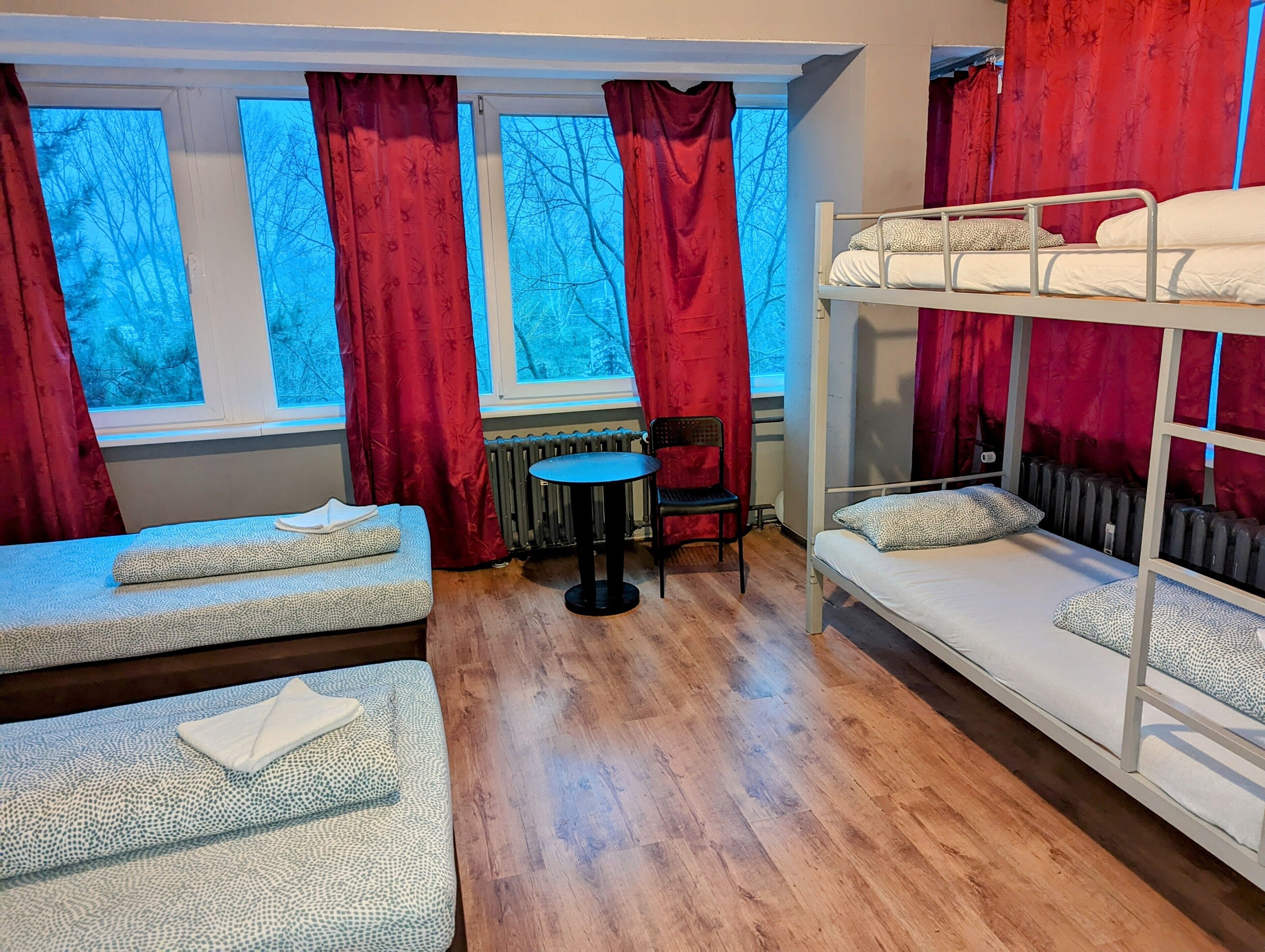 A dormitory room with bunk beds, a small table, and chairs.