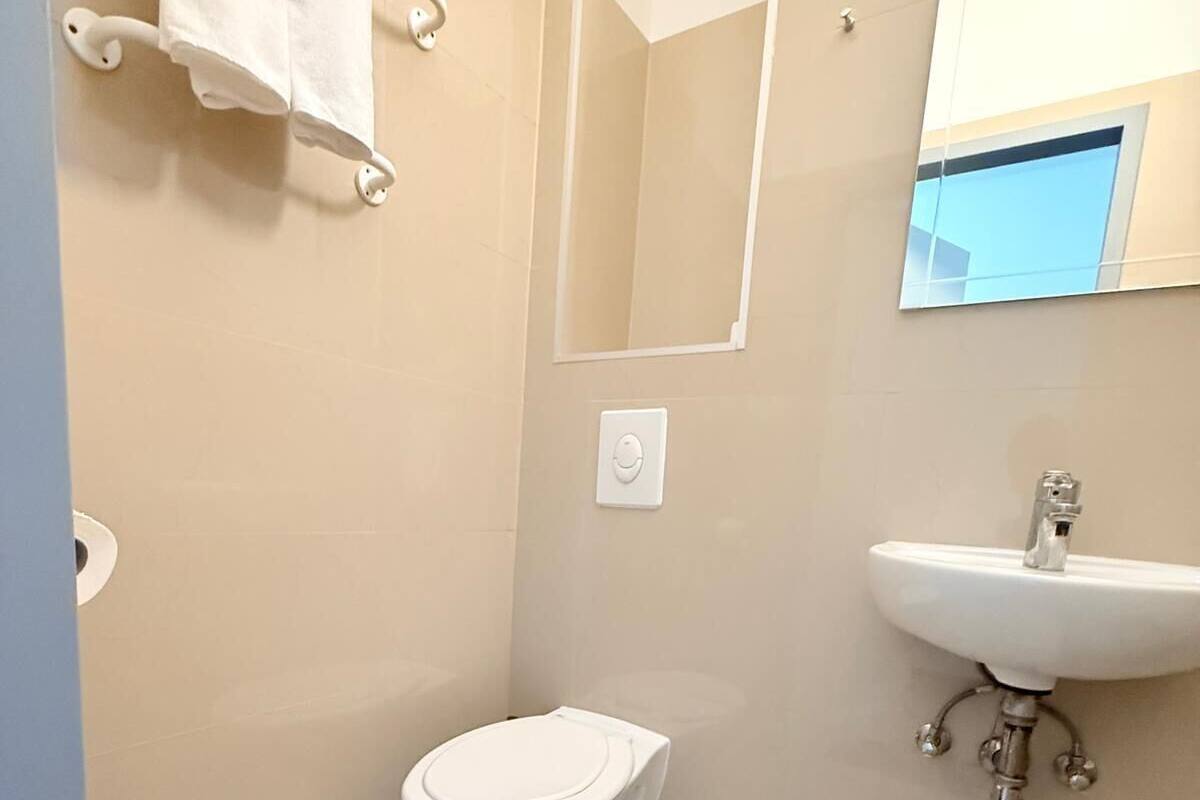 A bathroom with a toilet, sink, and mirror.