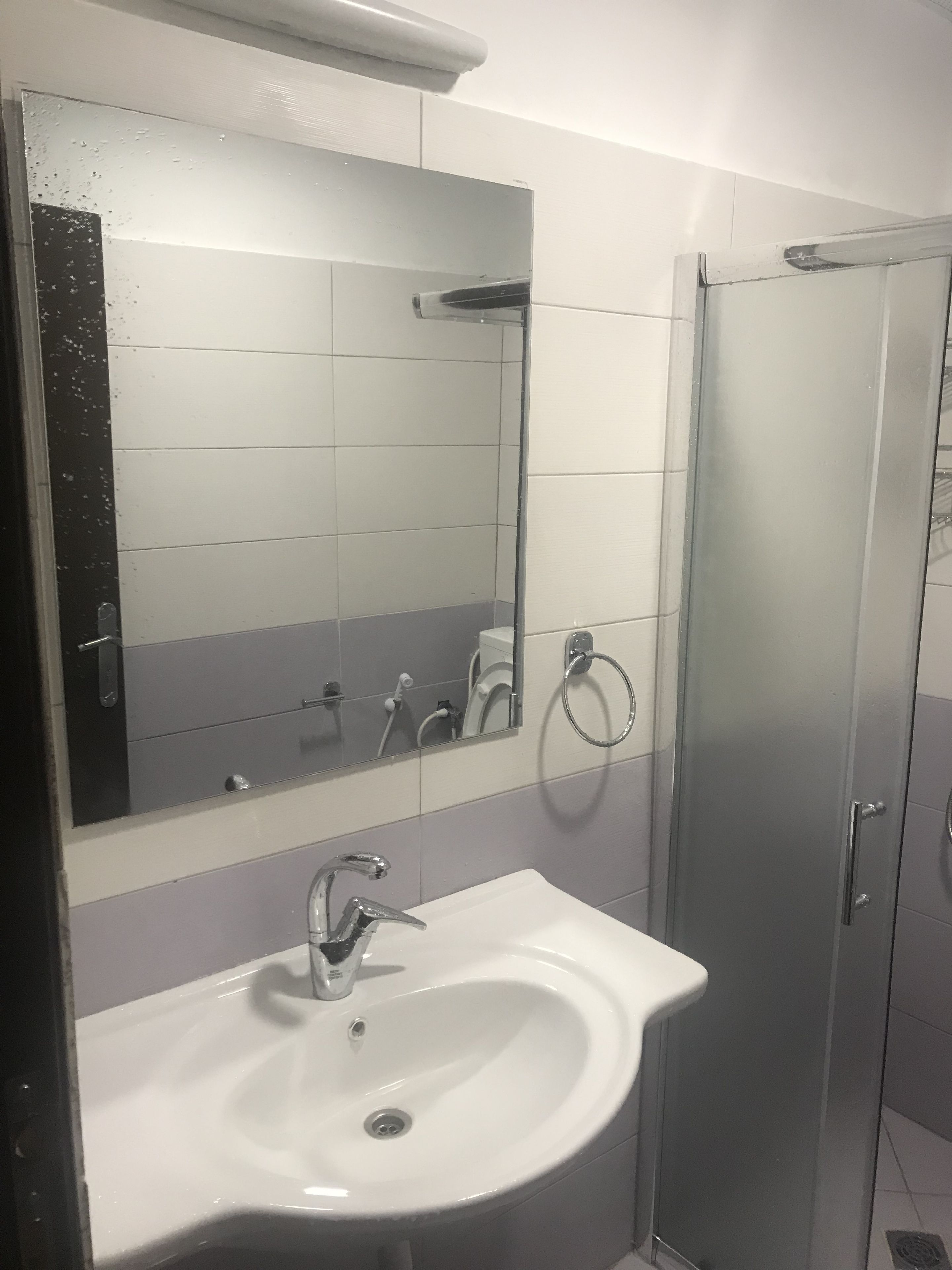 A bathroom with a white sink, a mirror, and a glass shower enclosure.