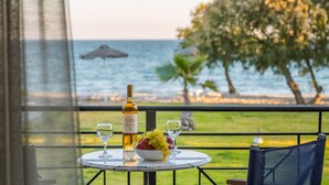 Une table avec une bouteille de vin, un bol de raisins et deux verres, le tout placé sur un balcon donnant sur la mer.