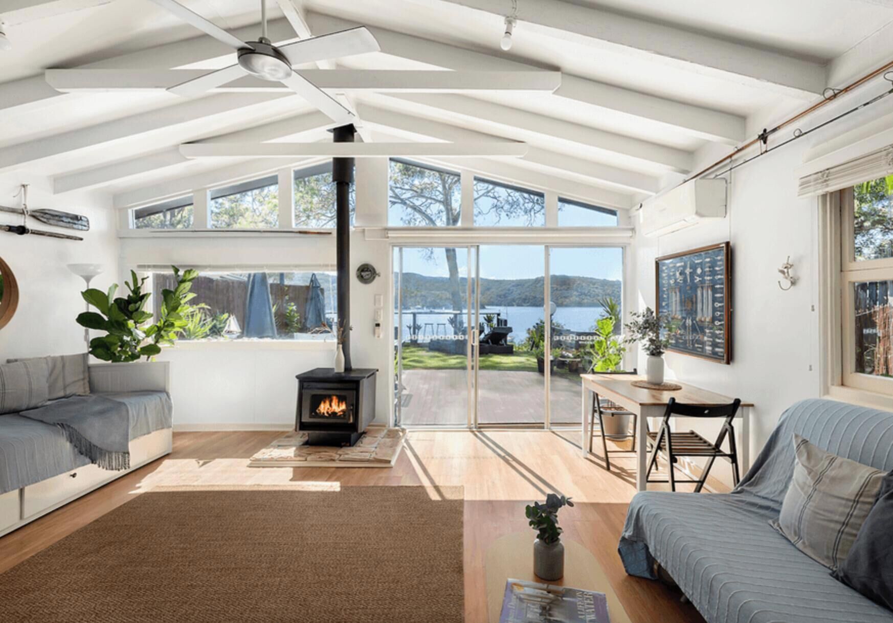 Amplia sala de estar con chimenea, sofá, mesa de comedor y vistas al exterior.