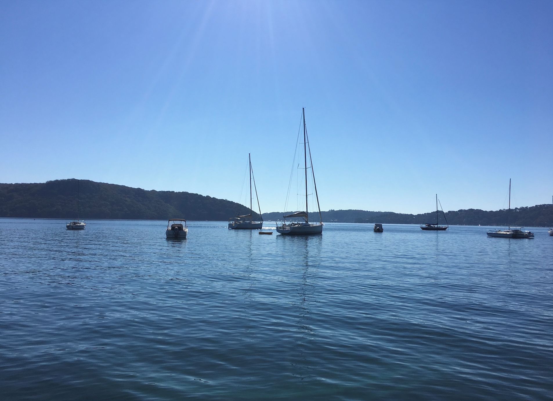 A calm body of water with several boats and a distant shoreline.