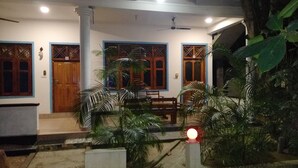 A building with three wooden doors, a covered porch, and a ceiling fan. - Hangloose Arugambay (Arugam Bay)
