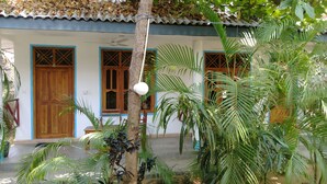 A house with a tiled roof, wooden doors, and a small porch area with potted plants. - Hangloose Arugambay (Arugam Bay)