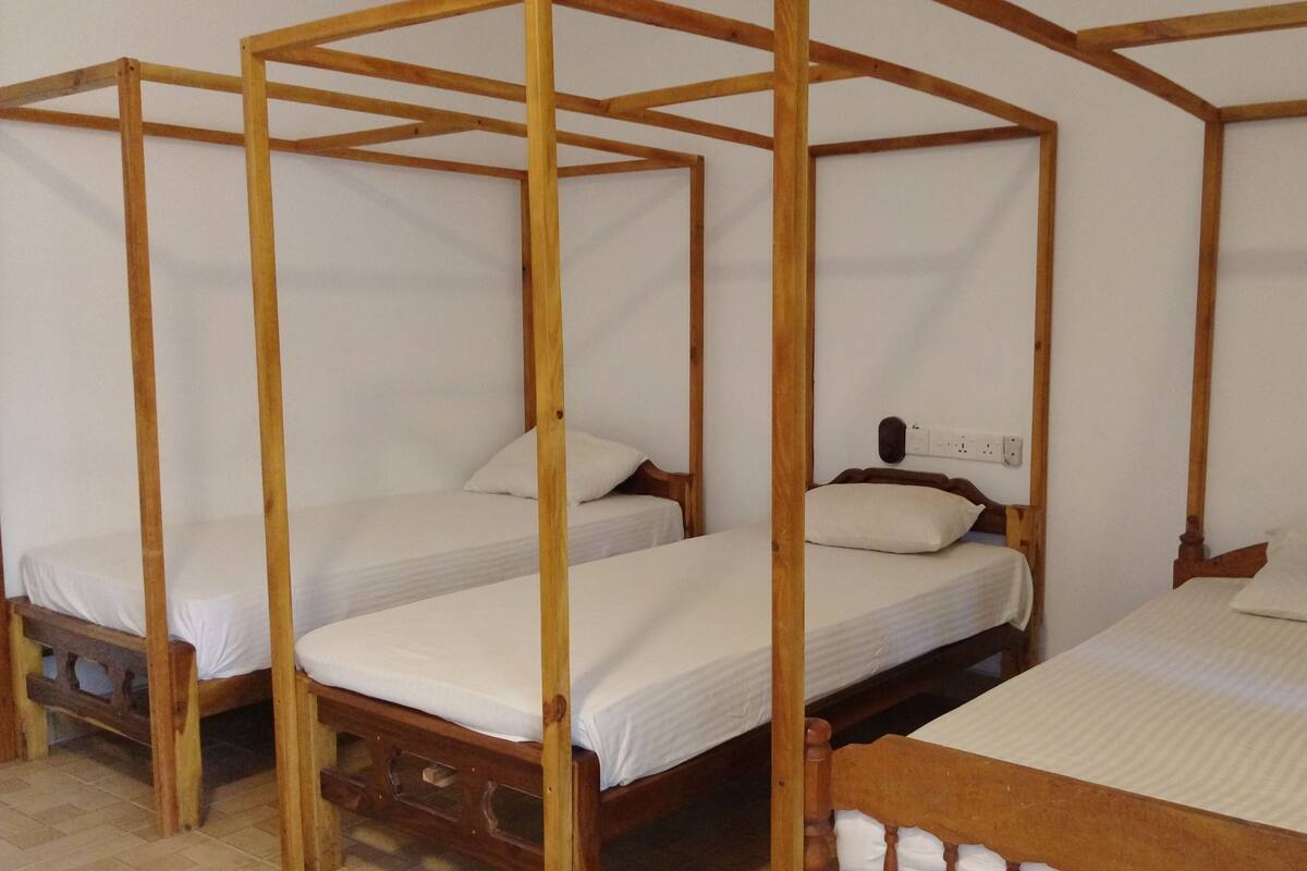 Een kamer met vier houten baldakijnbedden, op een rij geplaatst.
