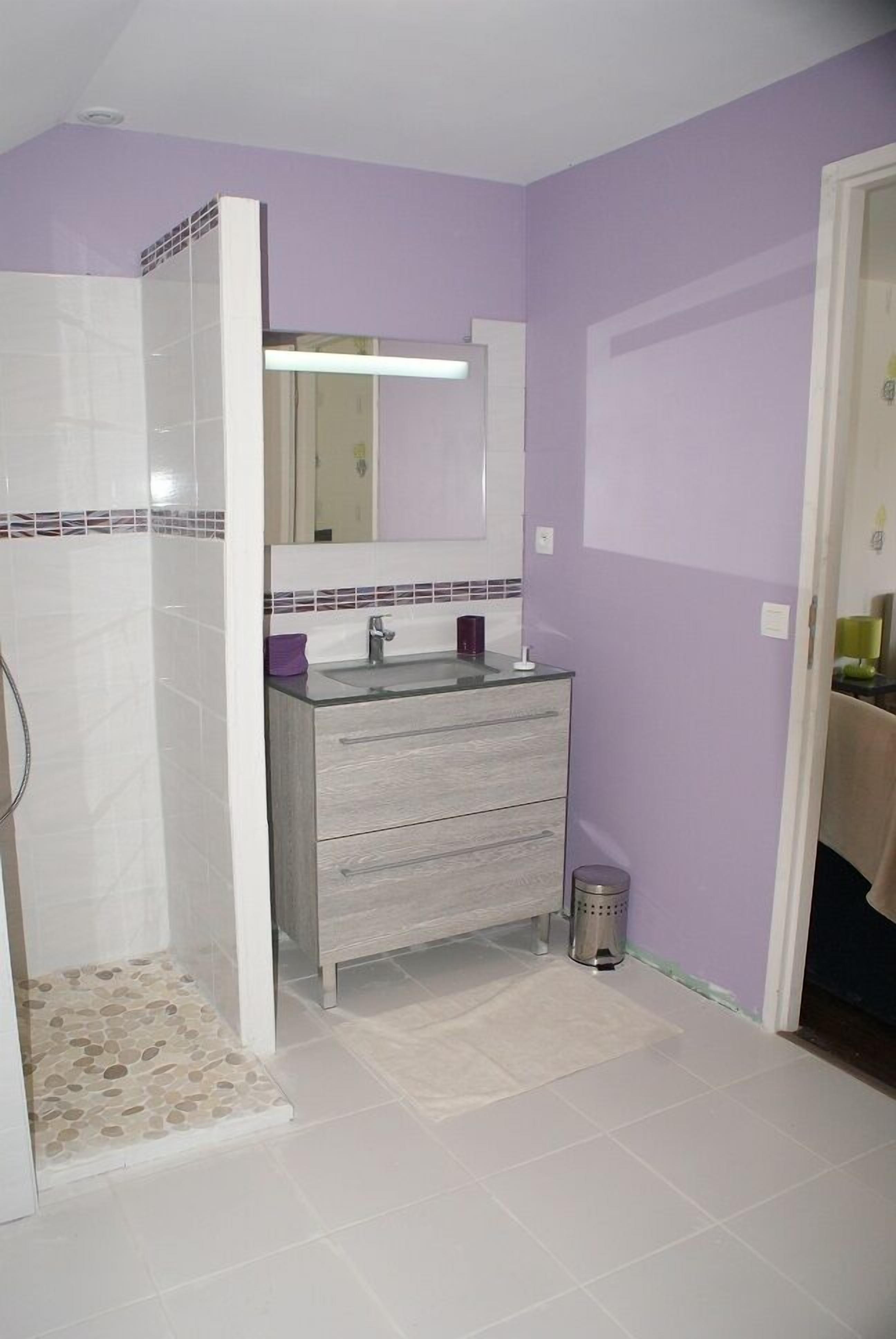 Ein Badezimmer mit Dusche, Waschbecken mit Spiegel und Fliesenboden.