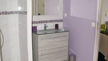 Ein Badezimmer mit Dusche, Waschbecken mit Spiegel und Fliesenboden.