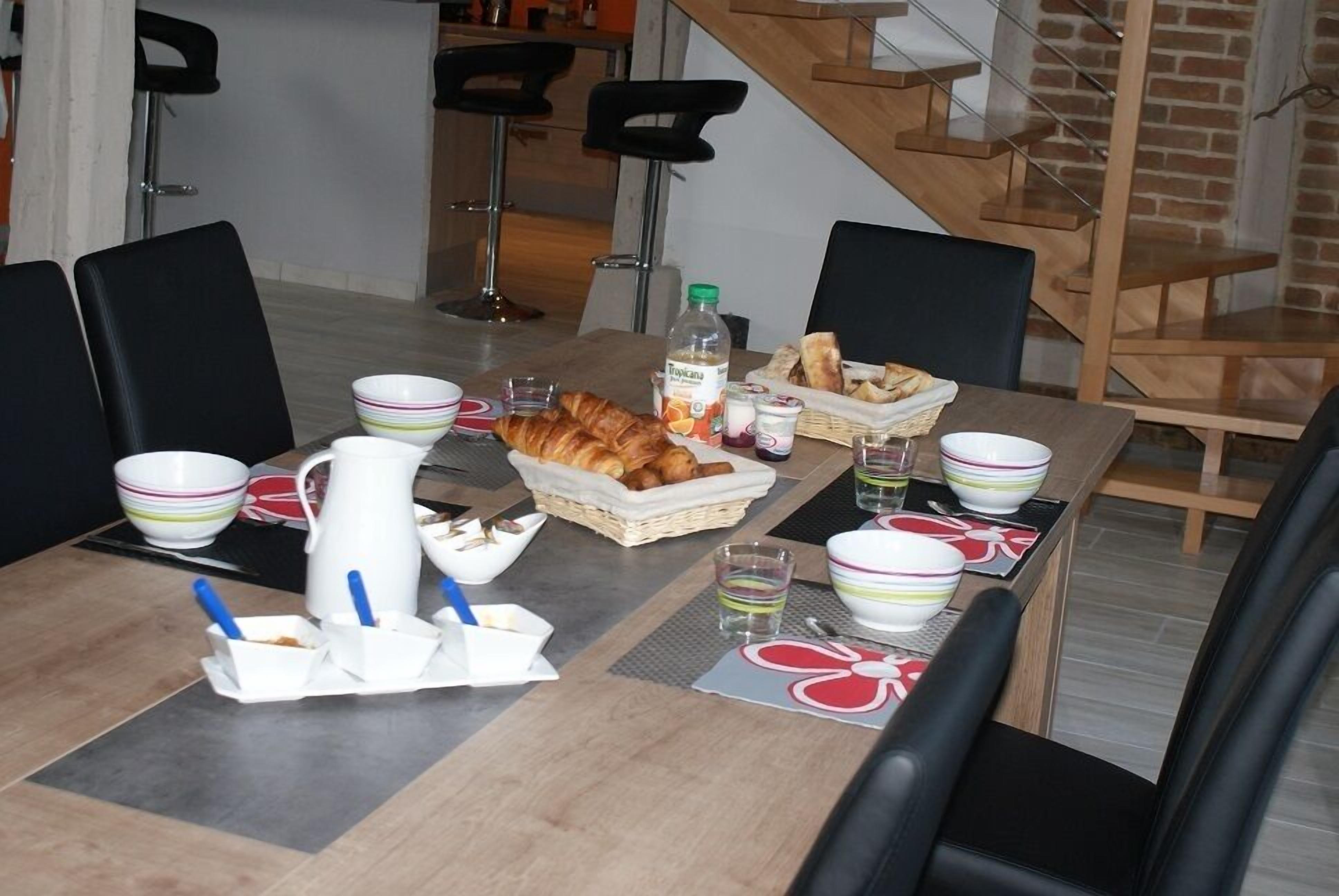 A dining table set with bowls, a pitcher, and a basket of bread.