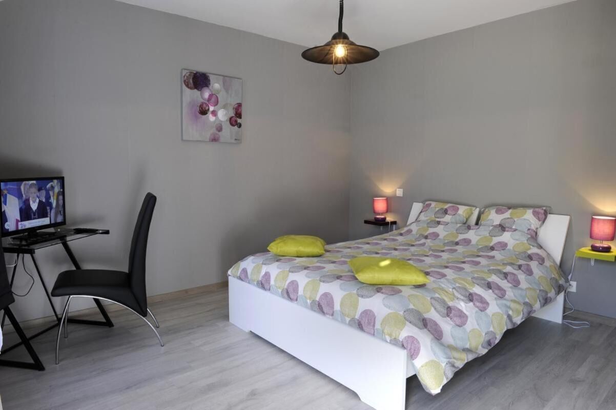 Une chambre à coucher comprenant un lit, un bureau, une chaise et deux lampes de chevet.