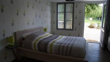 Un dormitorio con cama, lámparas de noche, ventana y puerta que da al exterior.