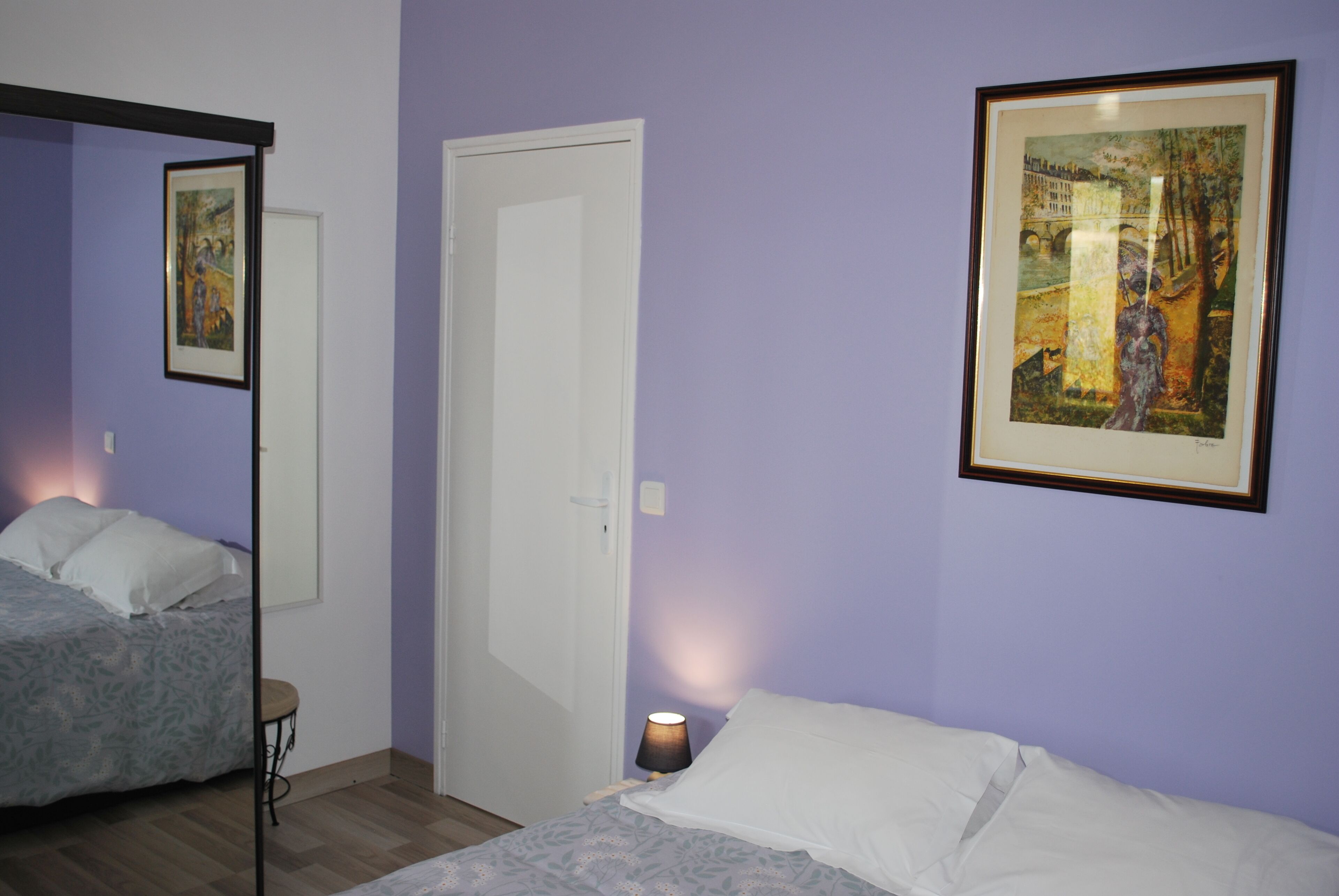 Quarto com duas camas, uma porta e um quadro na parede.