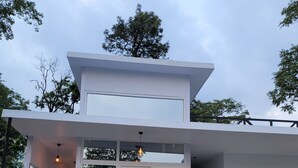 A modern two-story house with a flat roof, large windows, and a covered porch area. - Indian Culture Hostel (Narendranagar)