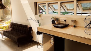 A modern kitchen with a dark brown sofa, a marble countertop, and skylights. - Indian Culture Hostel (Narendranagar)
