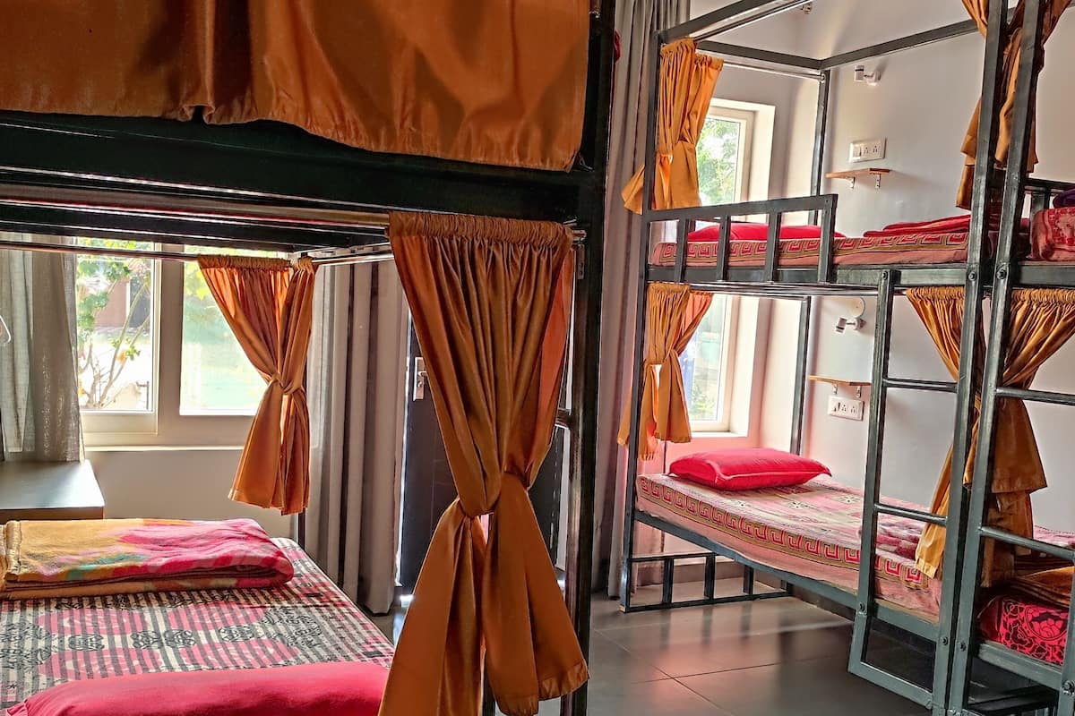A dormitory room with bunk beds, curtains, and a ceiling fan.