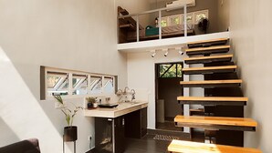 A modern interior with a staircase, a dining area, and a kitchen. - Indian Culture Hostel (Narendranagar)