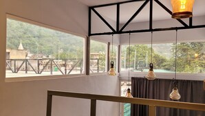 A room with a bed, a view of a bridge, and hanging light fixtures. - Indian Culture Hostel (Narendranagar)