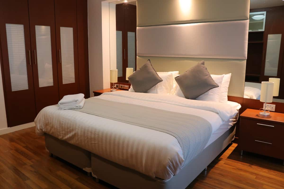 Una habitación de hotel moderna con una cama grande, un armario de madera y un televisor de pantalla plana.