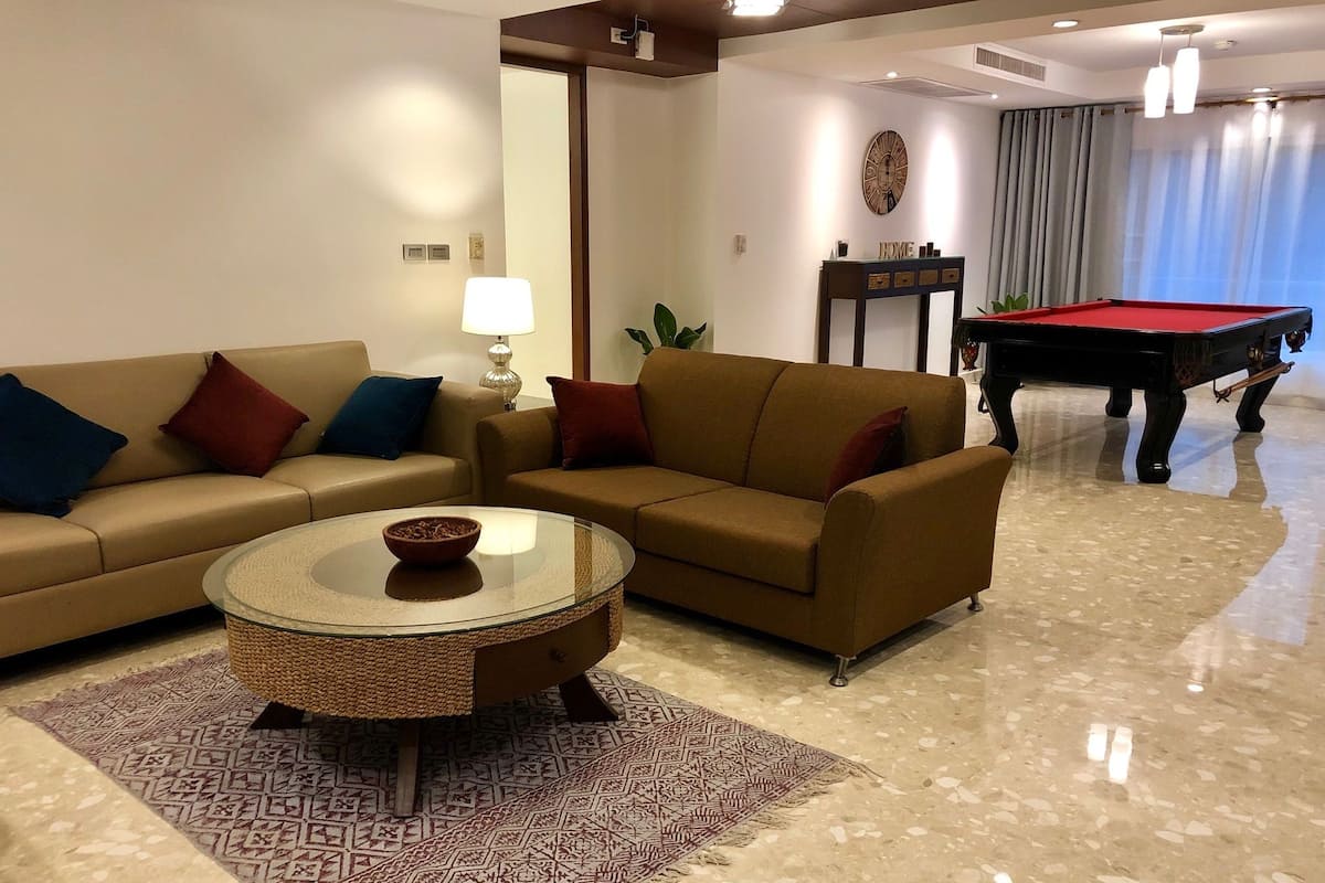 Una sala de estar con dos sofás, una mesa de centro, una mesa de billar y una lámpara.