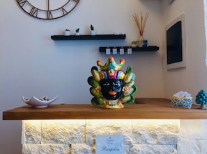 Ein Empfangsbereich mit einem dekorativen Keramikkopf, einer Uhr und einem Schild mit der Aufschrift 'Regina Elena Reception'.