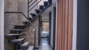 A modern staircase with a minimalist design, leading to a hallway with a wooden panel wall and a view into another room. - 3 BEDROOM PENTHOUSE MIDDLE OF PARK LLERAS PRIVATE ROOF TOP WITH HOT TUB AC (Medellin)