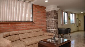 A living room with a beige sectional sofa, a glass-top coffee table, and a brick accent wall. - Lower Penthouse Two Bedroom AC DECK with Hot Tub Elevator AC (medellin)