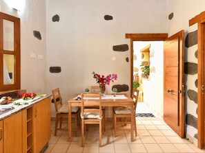 A kitchen with a wooden table, chairs, and a countertop with kitchen items.