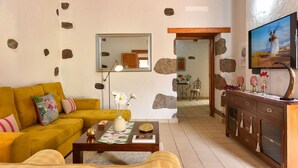 A living room with a yellow sofa, a wooden coffee table, and a TV mounted on the wall.